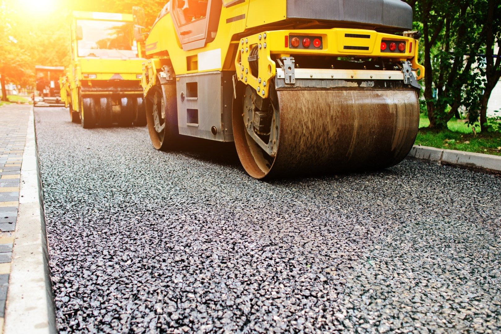 A yellow roller is rolling asphalt on a road.