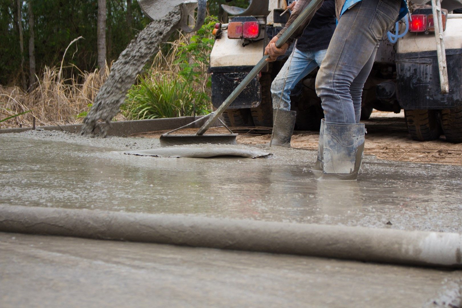 A couple of men are working on a concrete floor.