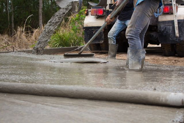 A couple of men are working on a concrete floor.