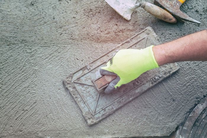 A person is using a trowel on a concrete surface.