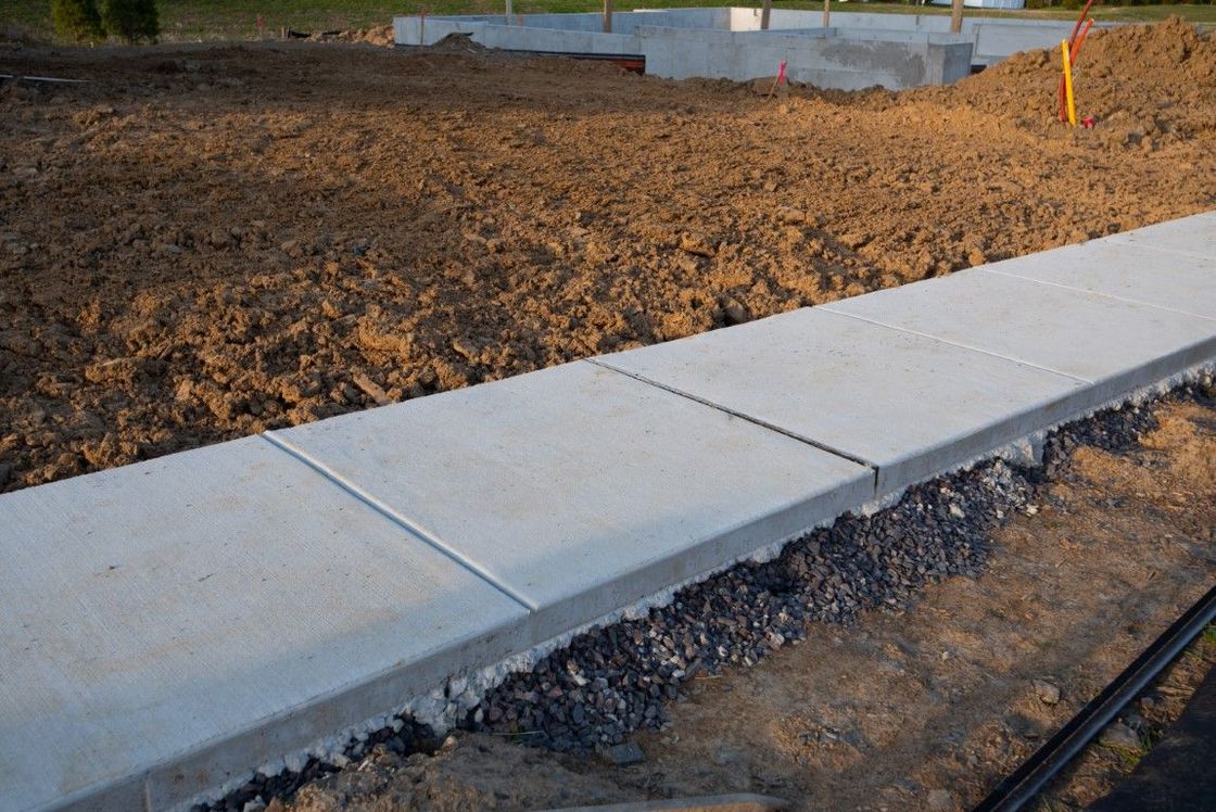 A concrete sidewalk is being built in a dirt field.