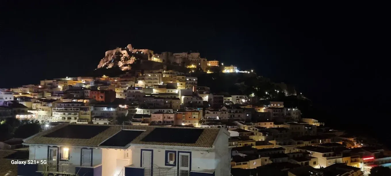 Un villaggio collinare di notte, con finestre e lampioni luminosi che si stagliano contro un cielo scuro.