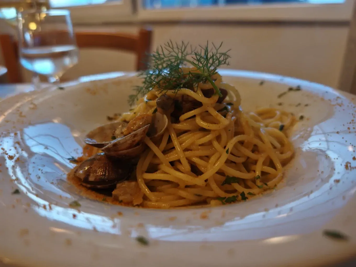 Un piatto di spaghetti alle vongole, guarnito con erbe aromatiche fresche, servito in un ristorante.