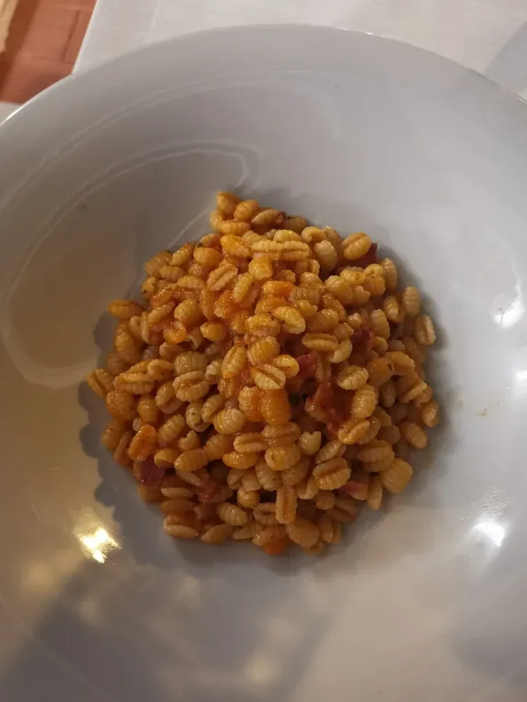 Una piccola porzione di farro o orzo cotto con una salsa rossastra leggera, servita in una ciotola bianca.