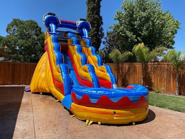 A large inflatable water slide is sitting in the backyard of a house.