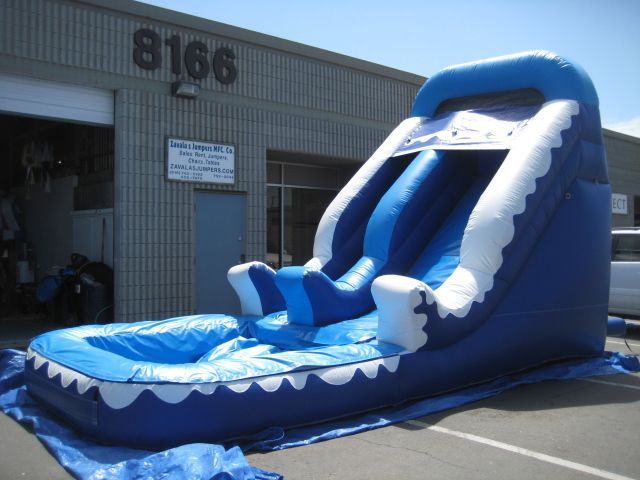 An inflatable water slide is sitting in front of a building with the number 8166.