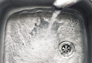 Water flows into a stainless steel sink, filling around the drain.