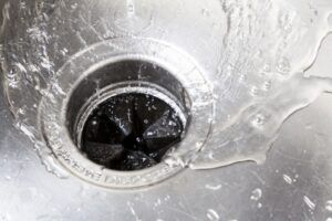 Sink drain with water flowing in, showing the garbage disposal unit.
