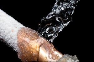 Frozen pipe bursting, spraying water against a black background.