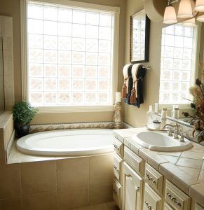 Bathroom with soaking tub, glass block windows, light-colored cabinets, and a sink area.