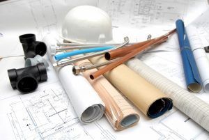 Construction materials, blueprints, a hard hat, and rolled plans.