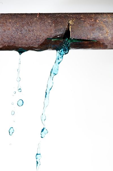 Rusty pipe leaking blue water.
