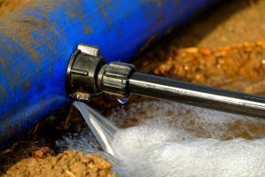 A blue pipe connected to a black pipe, leaking water onto the ground.