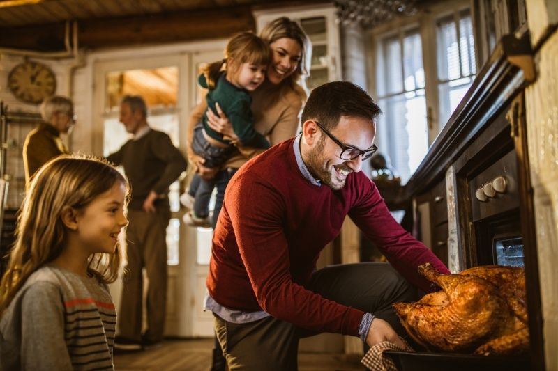 Family in kitchen preparing a turkey for a holiday meal.