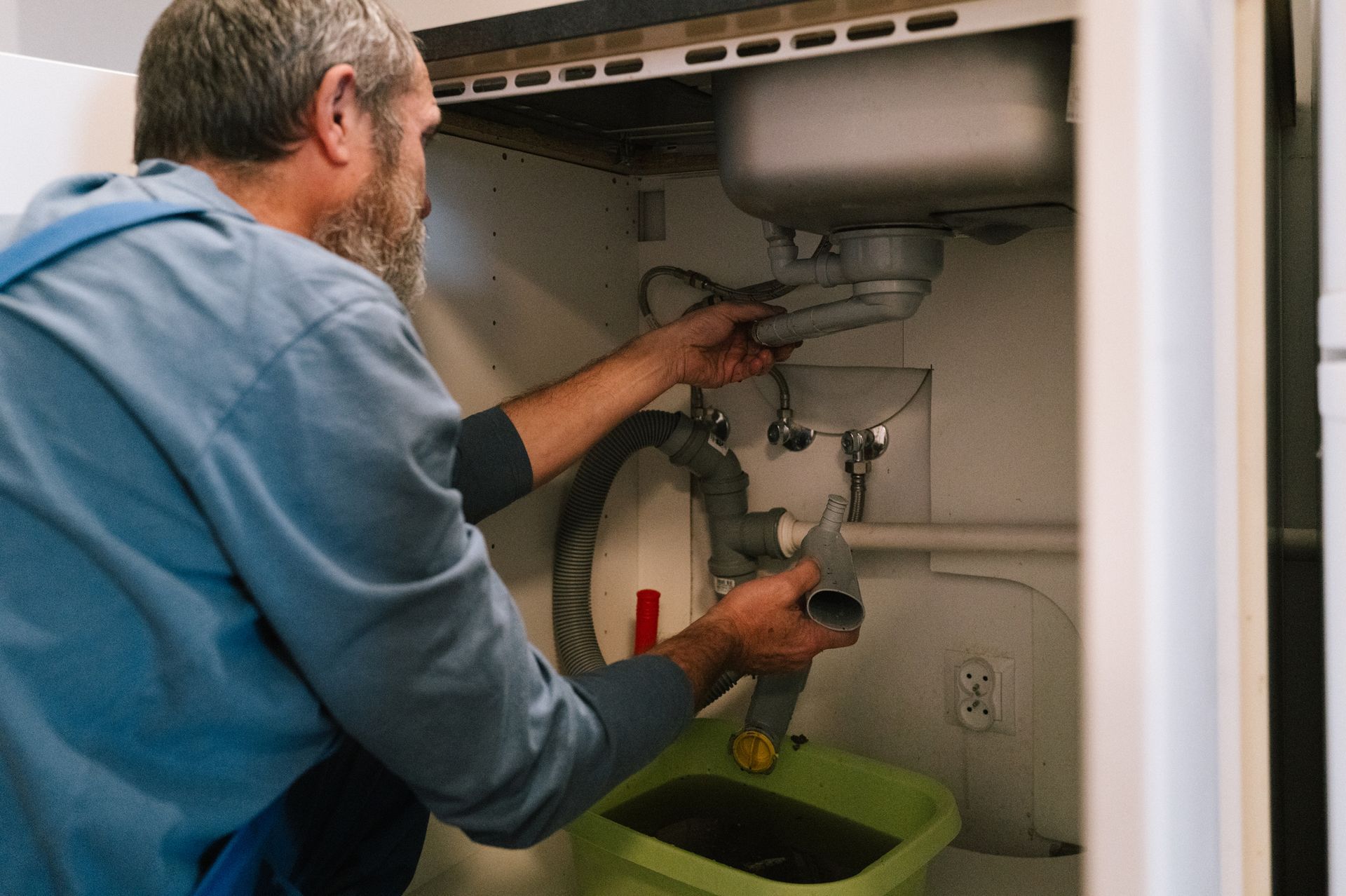 Plumber repairing blocked kitchen drain during leak detection service in Olympia Washington.