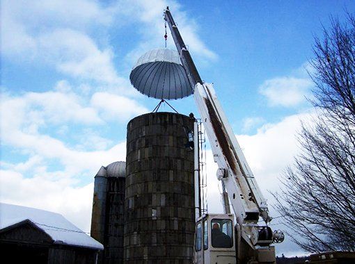 A crane is lifting a parachute over a silo