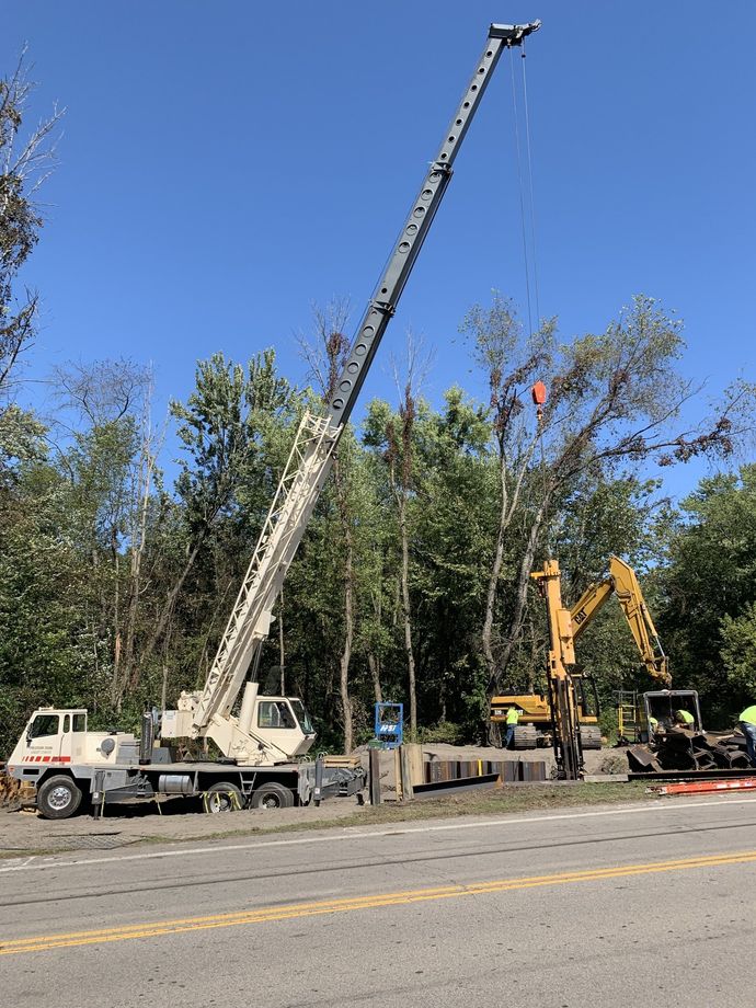 A crane is lifting a tree in the middle of a road.