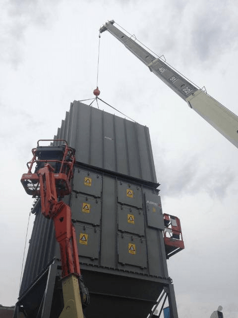 A crane is lifting a large container with the letters ee on it