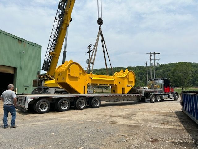 A crane is lifting a large yellow object on a trailer