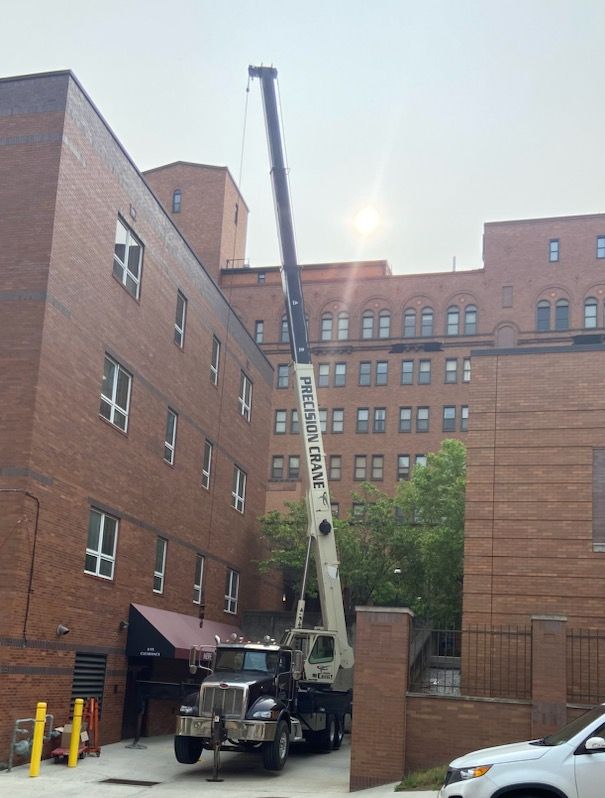 A pelican crane is parked in front of a large brick building