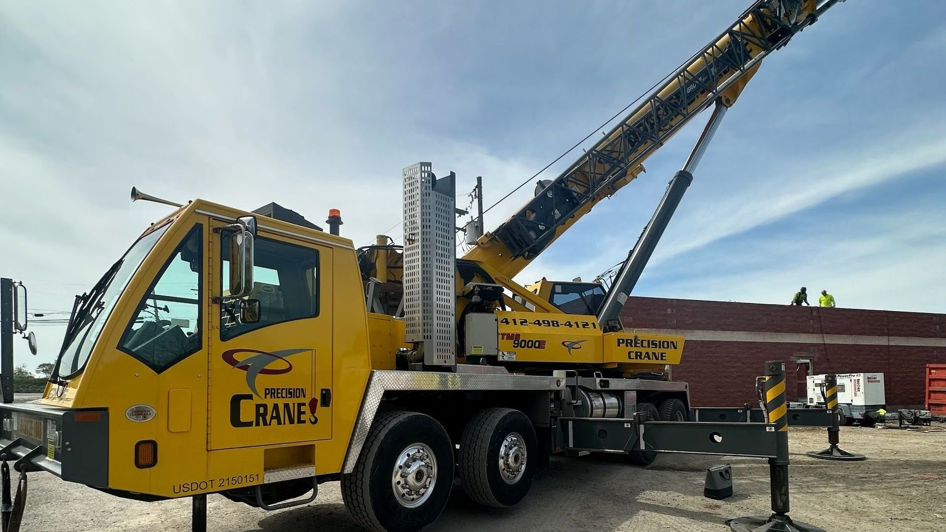 A large yellow crane is parked in front of a building.