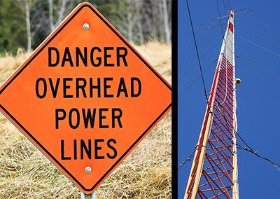 A danger overhead power lines sign next to a power tower