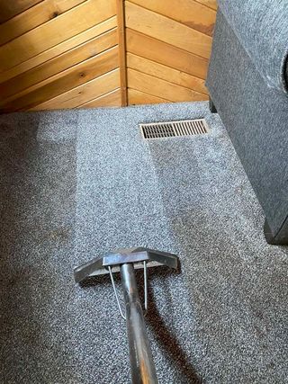 A vacuum cleaner is cleaning a carpet in a room.