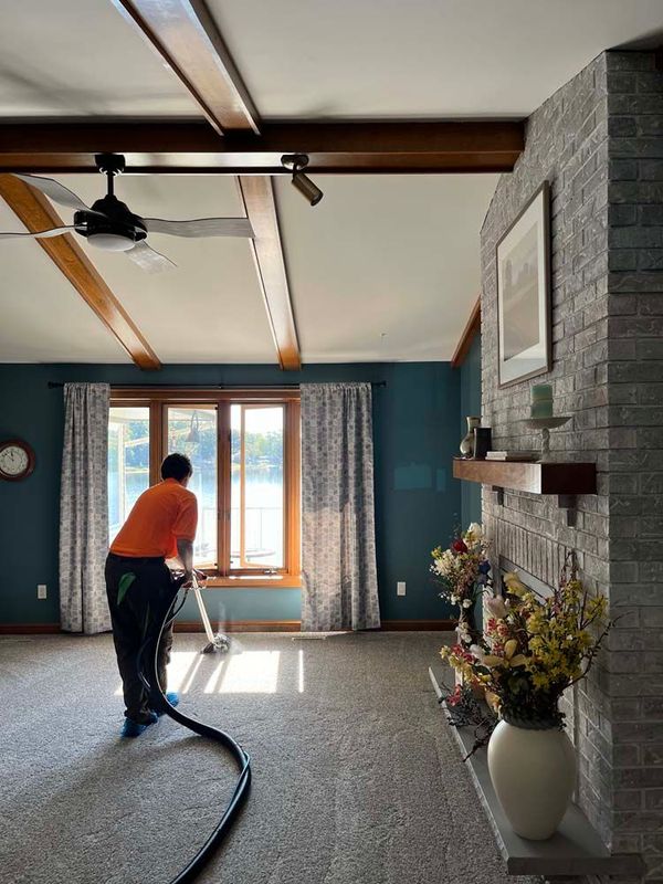 A man is vacuuming a carpet in a living room.