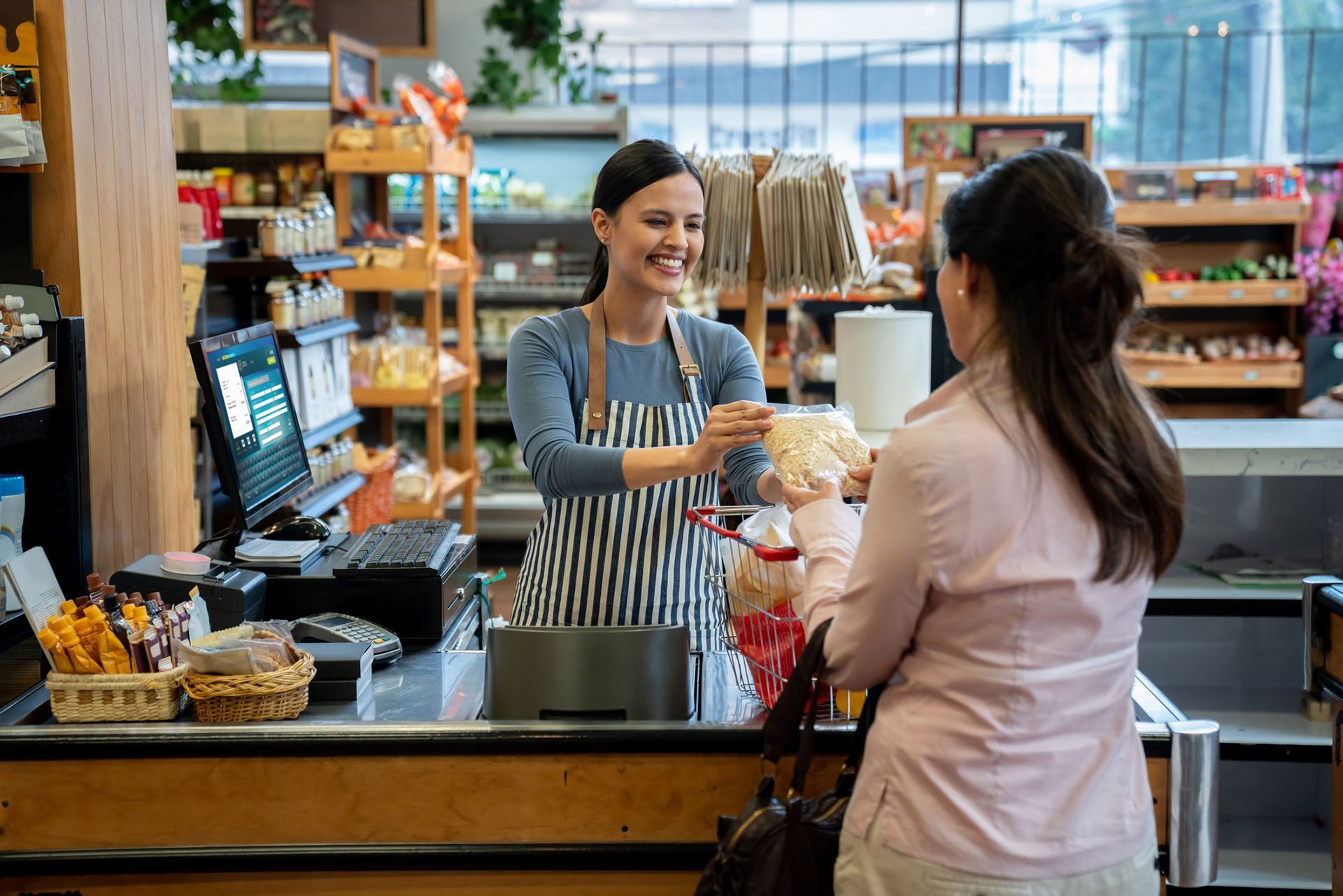 Customer at supermarket handing products to friendly cashier 