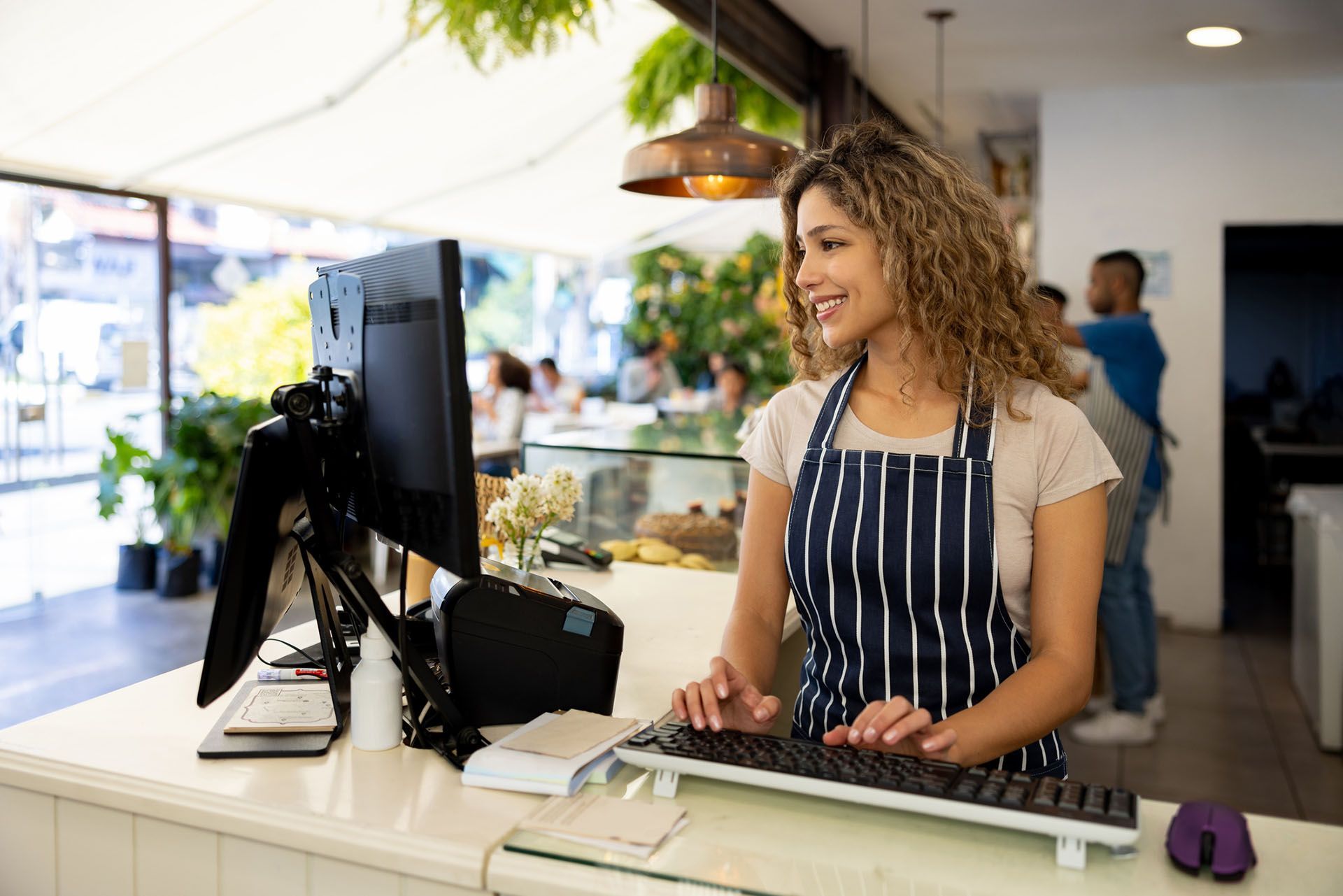 A member of staff at a farm shop smiles as she operates an EPOS terminal