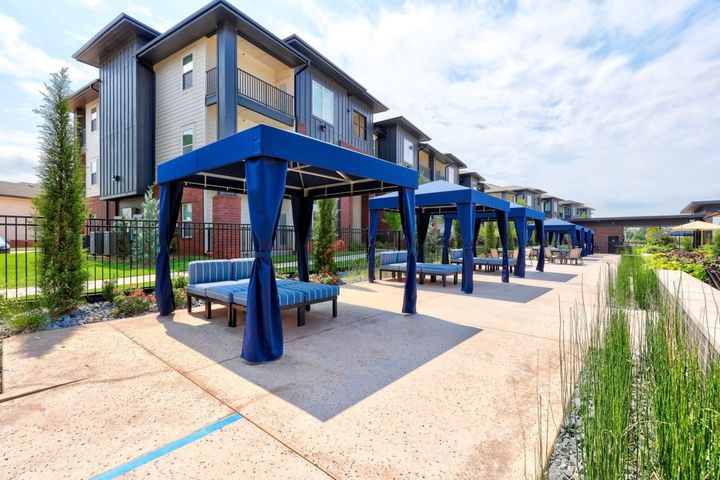 Outdoor seating area with blue cabanas and apartment building.