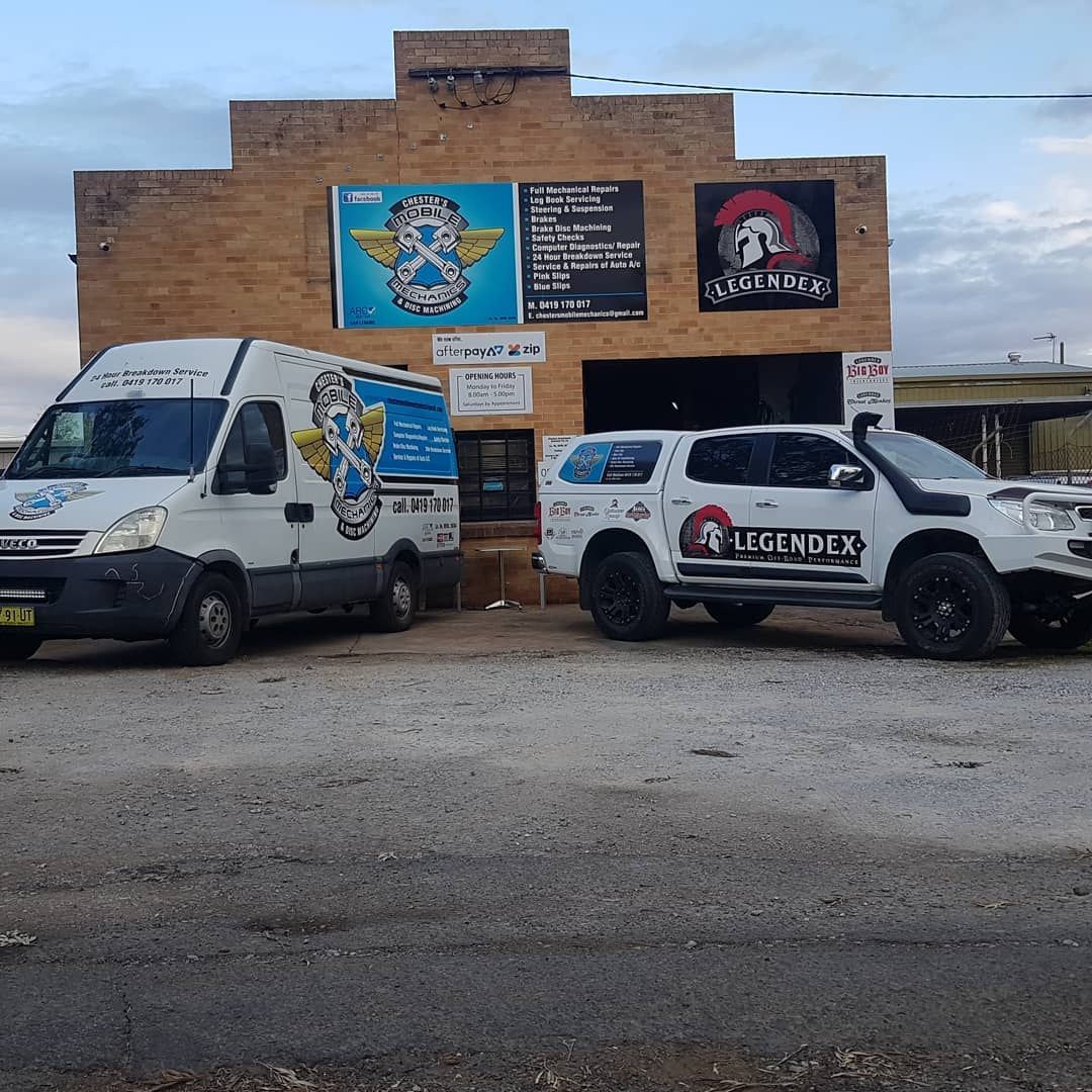 A White Van and Truck Parked in Front of a Brick Building — Chester's Mechanical & Performance in Tamworth, NSW