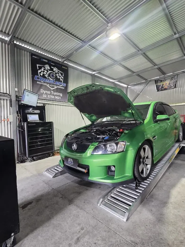 Green Car on a Dyno Machine Inside a Workshop, Hood Open — Chester's Mechanical & Performance in Tamworth, NSW