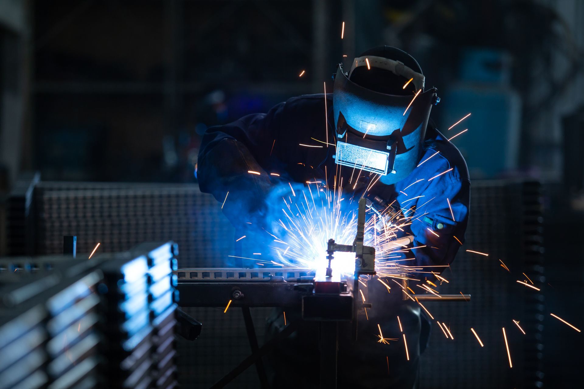 Worker wearing industrial uniform and welding steel