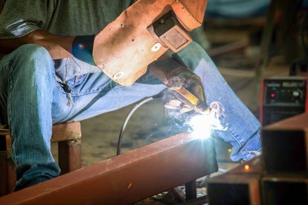 A man is welding a piece of metal in a factory.