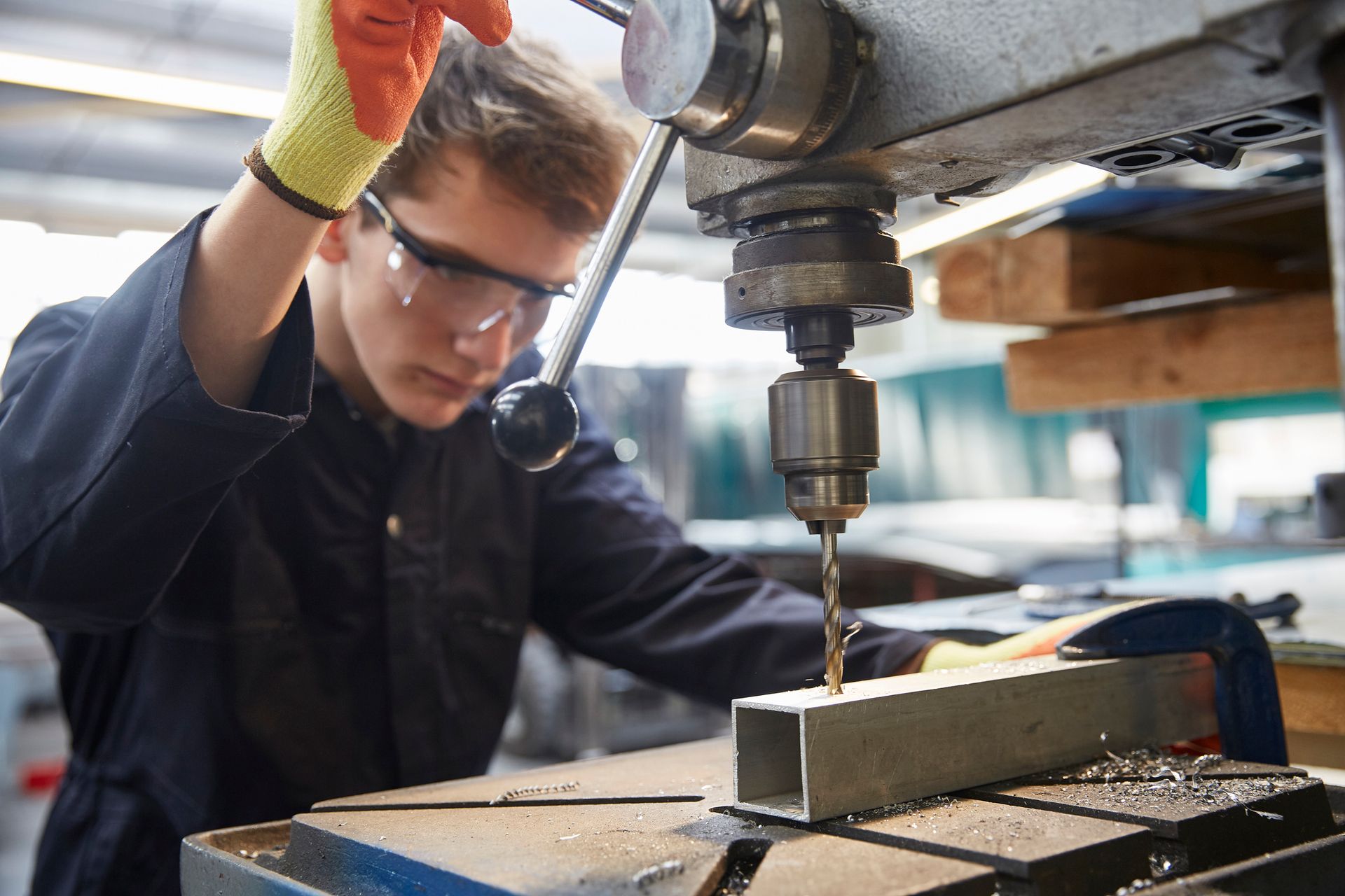 A man is using a machine to drill a hole in a piece of metal.