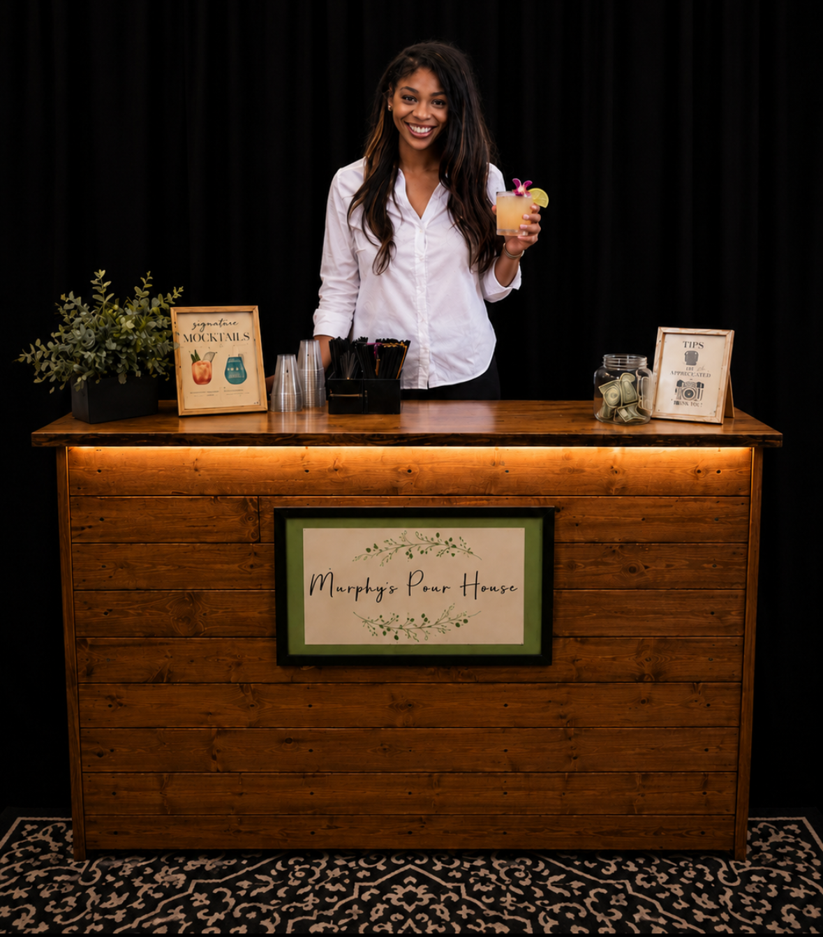 Person standing behind a wooden counter on a dark stage, gesturing with one hand