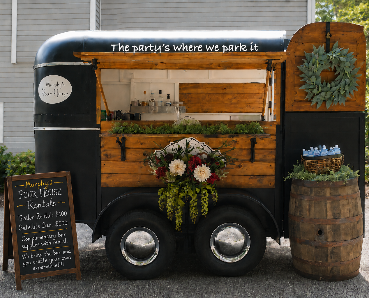 Wooden food truck with flowers, chalkboard menu, and wreath, parked against a gray wall.