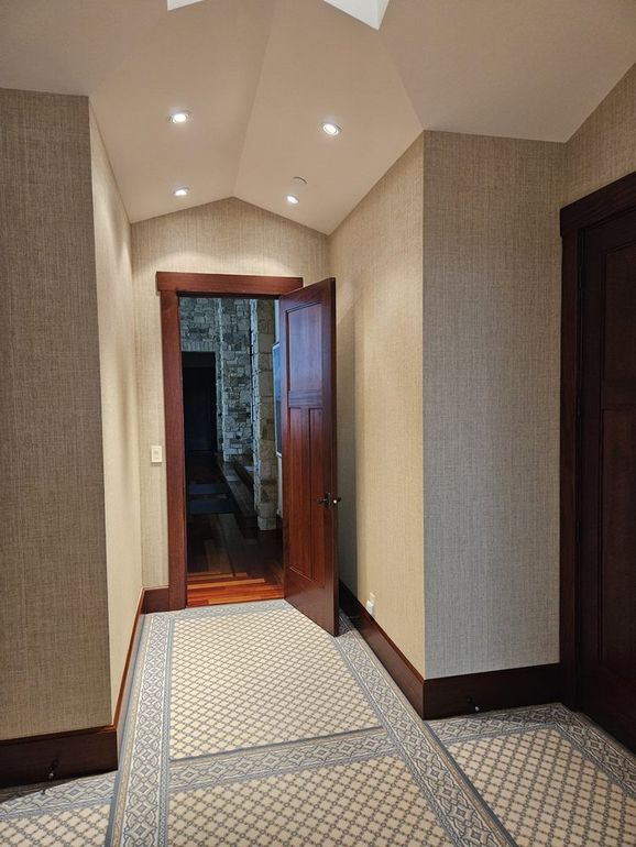A hallway with a door that is open and a rug on the floor.