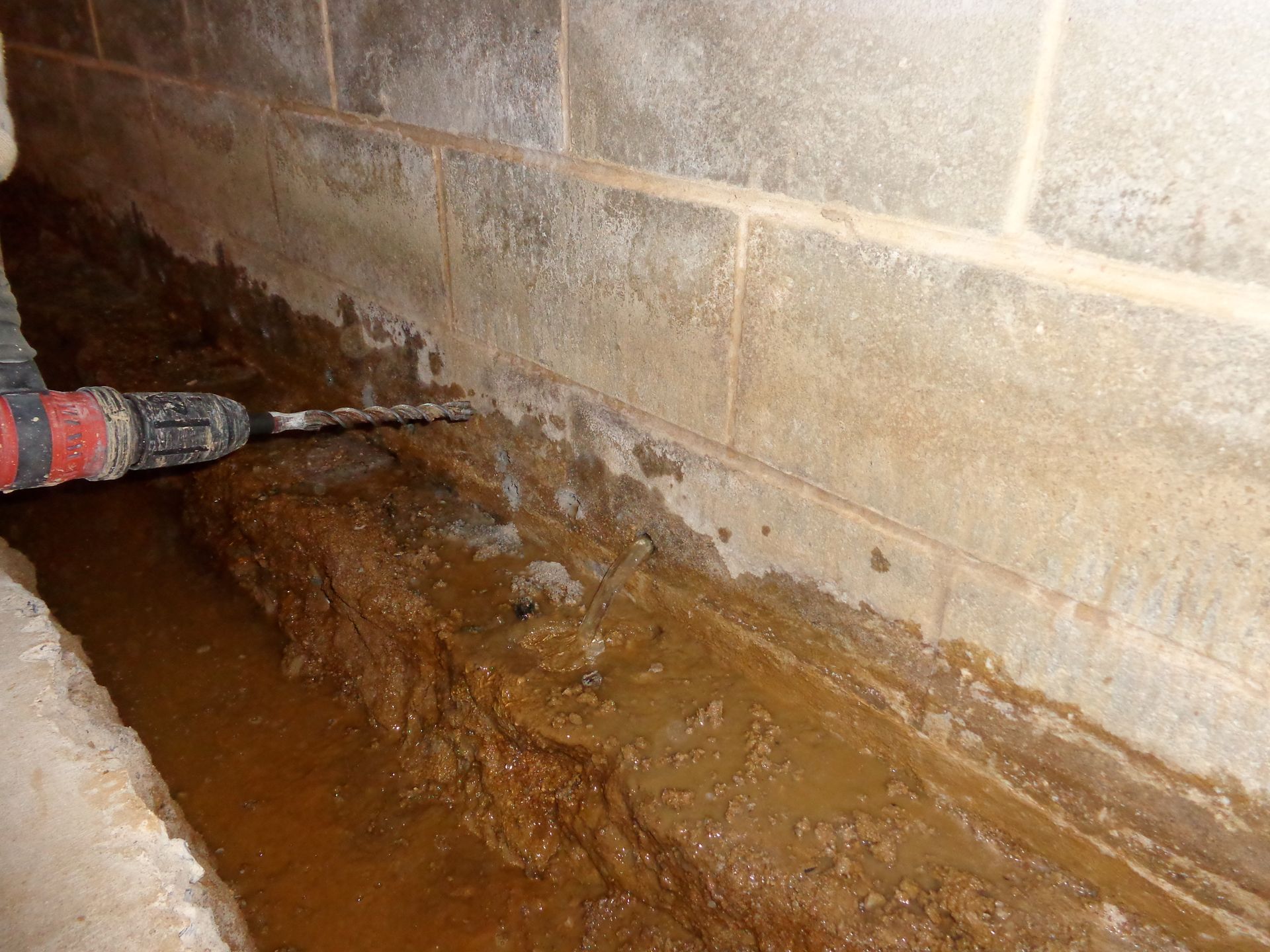 Drilling Weepholes in a cinderblock foundation full of water