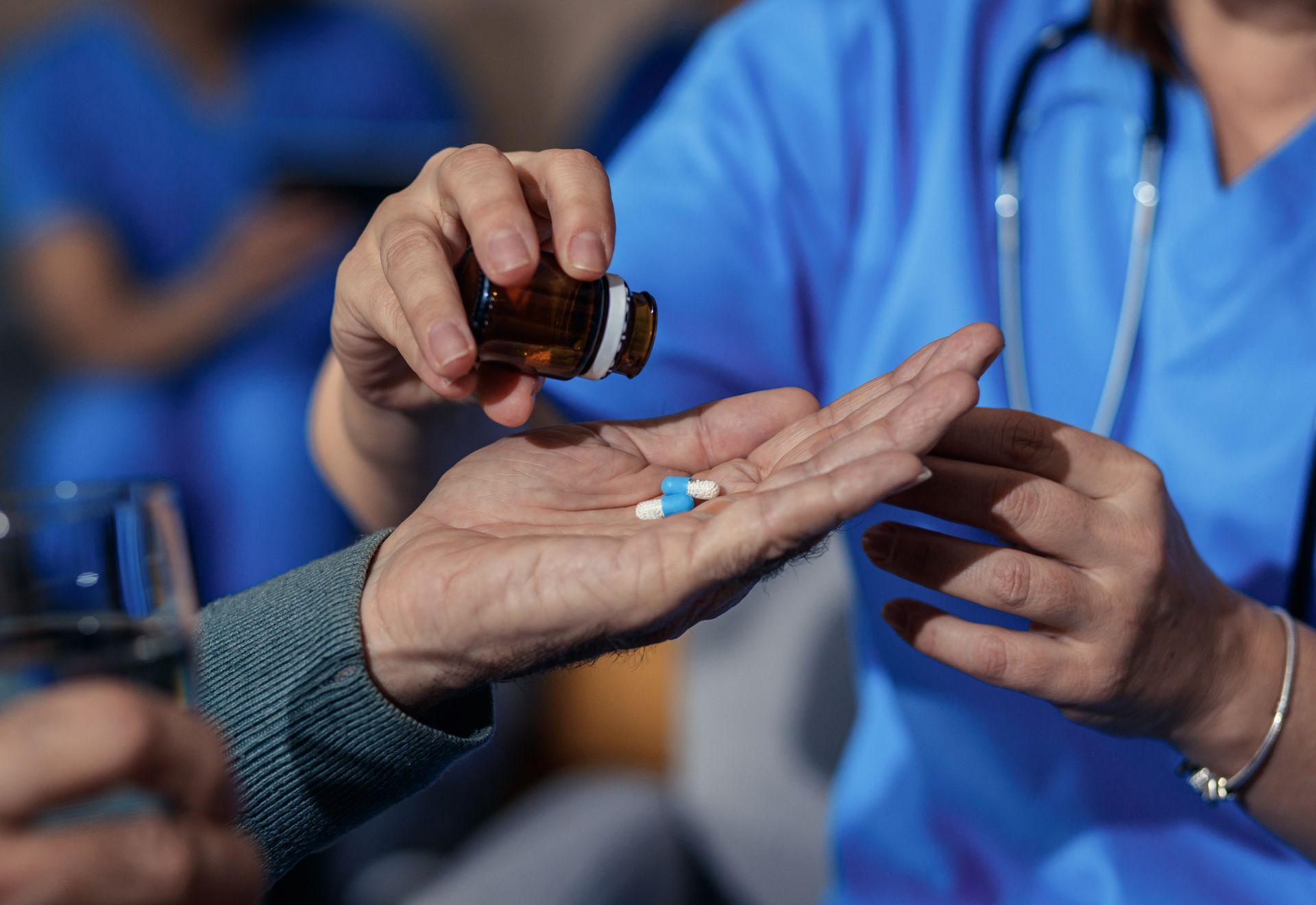 Nurse pours pills from a bottle into a patient's hand.