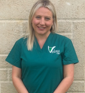 A person in a white coat holding the hand of an elderly person, offering support.