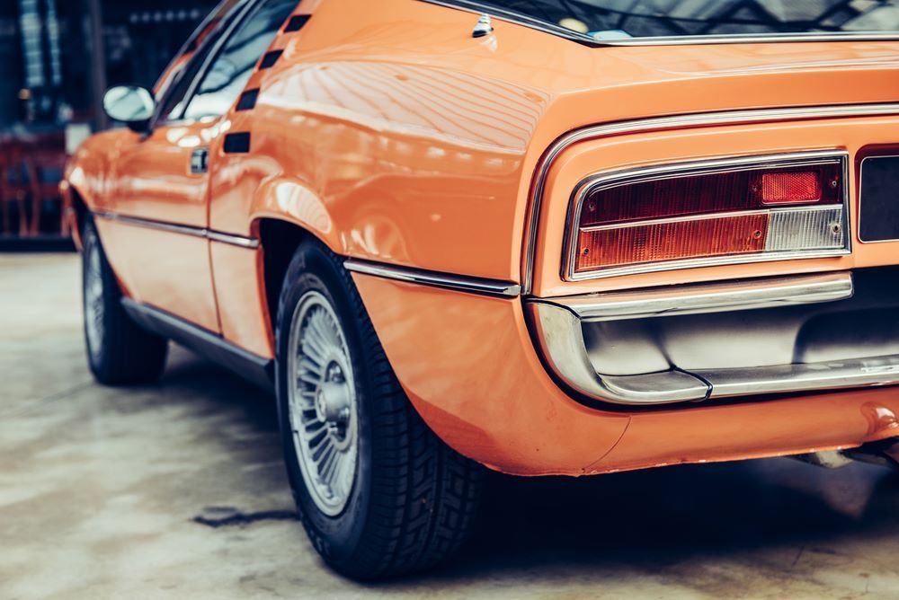 A Close Up of the Rear End of an Orange Car Parked in a Garage — About Town Windscreen Repairs & Replacements in Wulguru, QLD