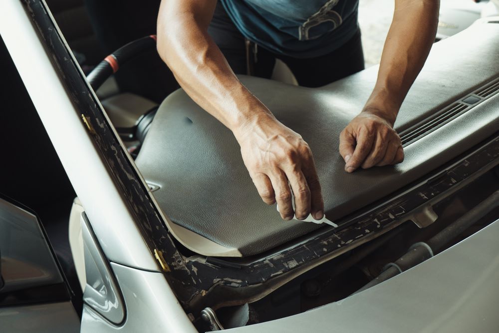 A Man is Working on the Hood of a Car — About Town Windscreen Repairs & Replacements in Wulguru, QLD