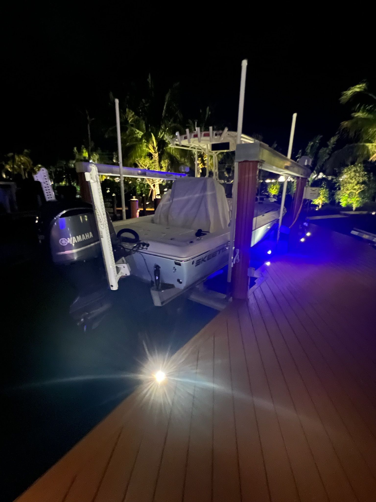 Boat docked at night with blue lights and spotlight illuminating the deck.