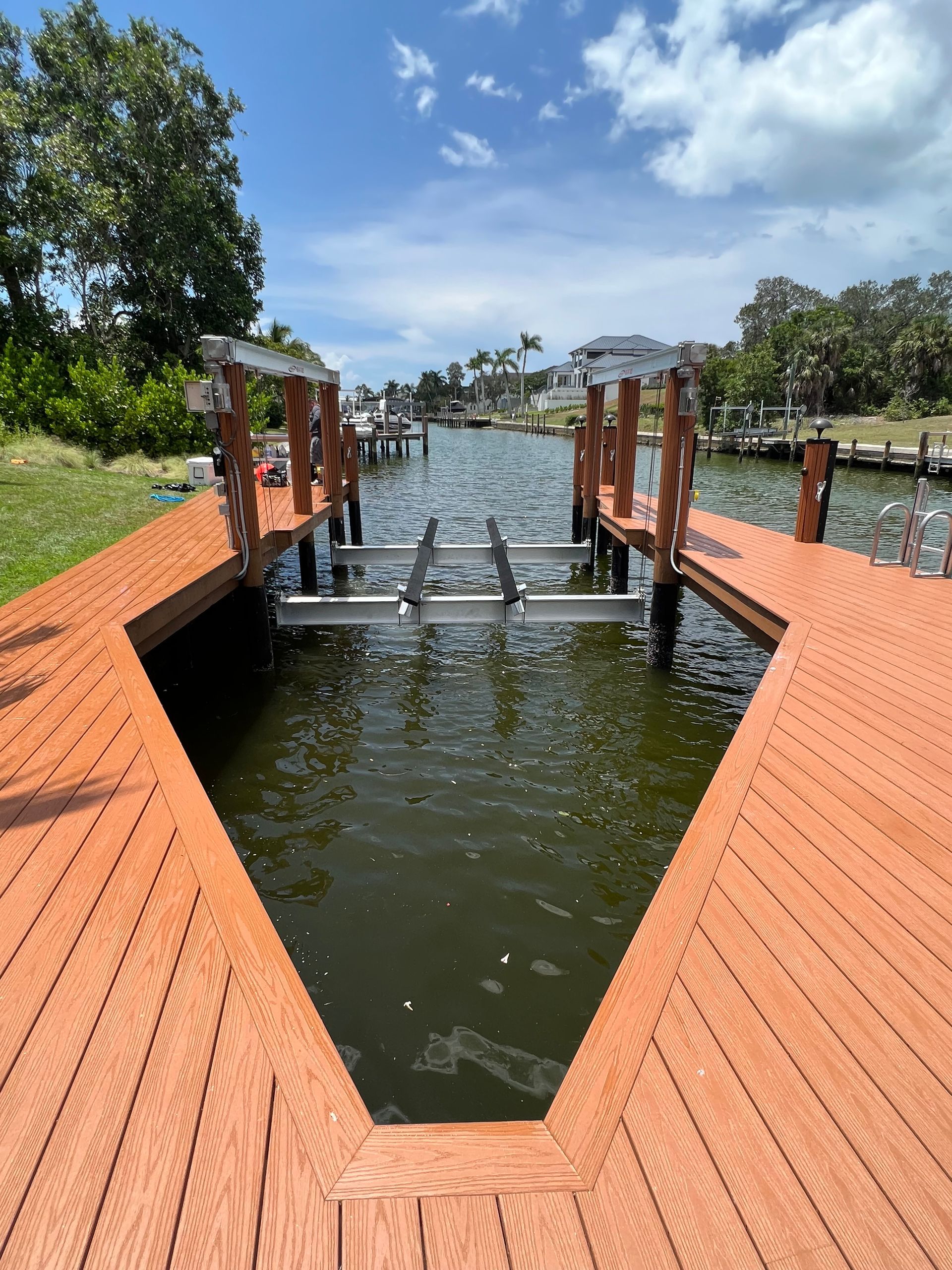 Wooden boat dock with lift in a waterway under a partly cloudy sky.