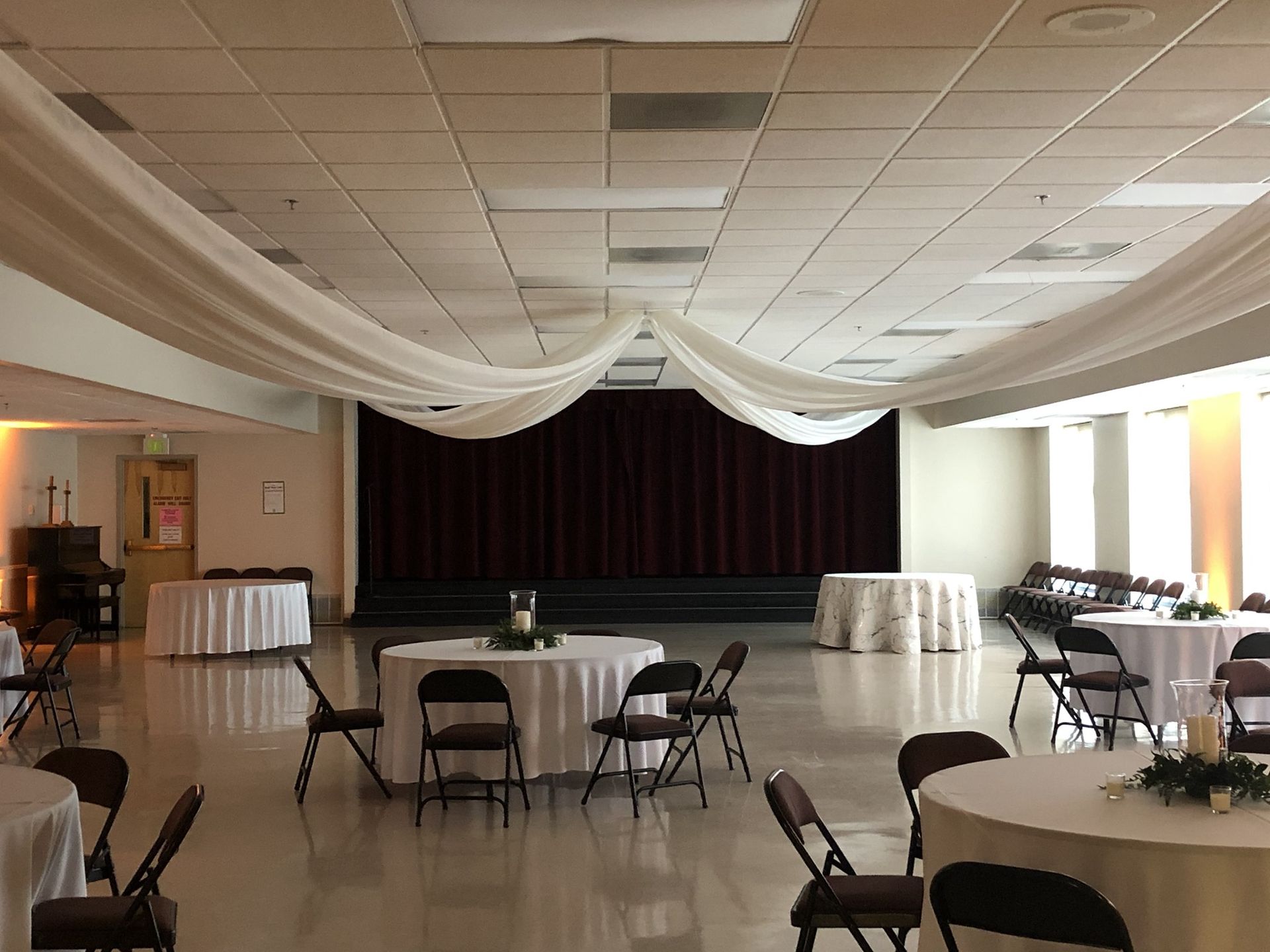 A large room with tables and chairs and a stage.