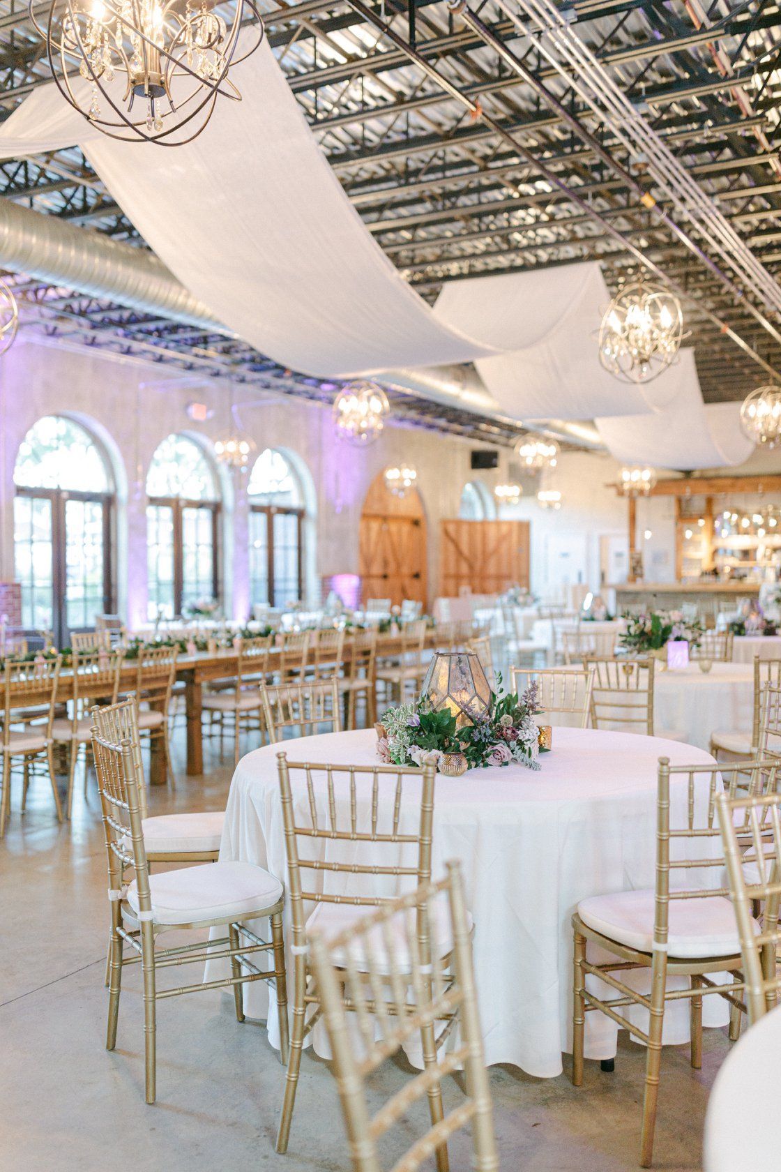 A large room with tables and chairs set up for a wedding reception.