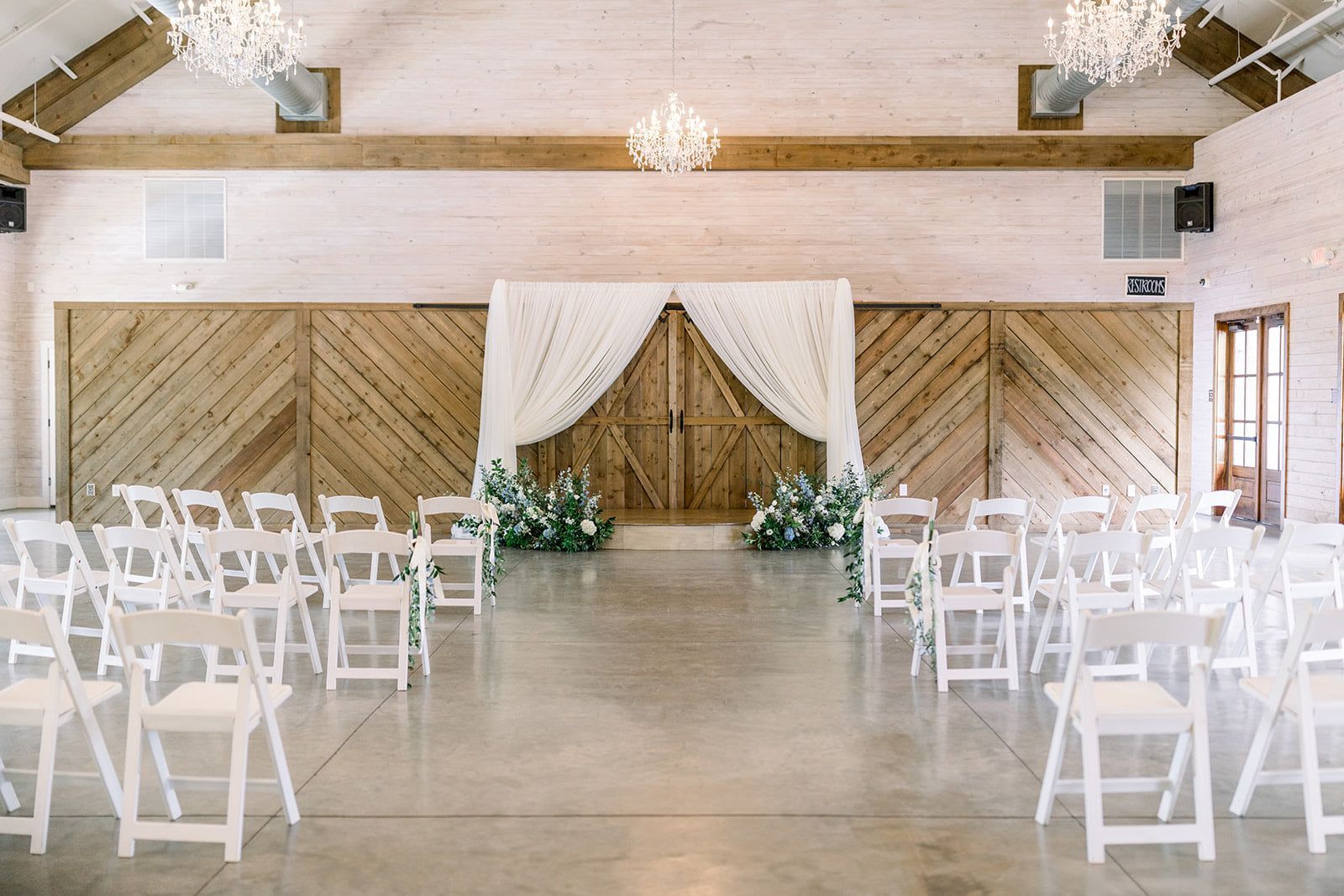 A large room filled with white folding chairs and a wooden archway.