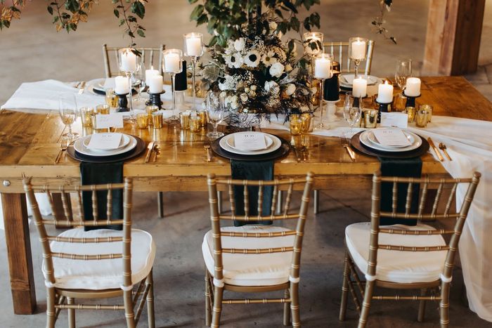 A wooden table with plates , candles , and flowers on it.